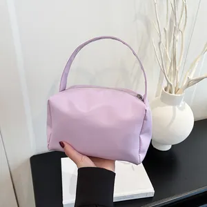 Close-up of light purple leather handbag featuring metal zipper and top handle detail