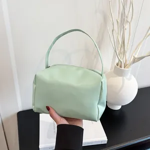 Handheld mint green PU leather handbag featuring a minimalist pillow-shaped design and long straps