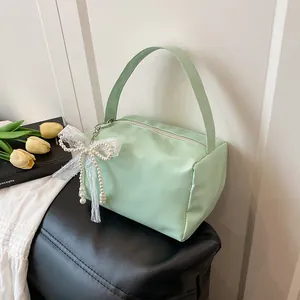Detail of mint green handbag with large white lace bow and elegant pearl charm detail