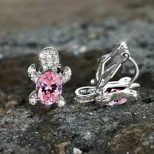 Close-up of turtle ear clips featuring pink oval gemstones and sparkling micro-crystals
