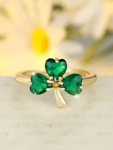 Macro shot of gold clover ring with three heart-shaped green stones and prong setting