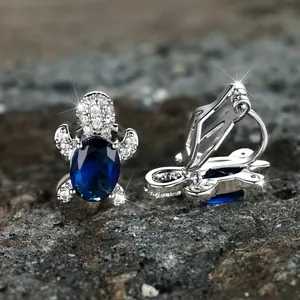 Creative turtle ear clip with deep blue gemstone and white zircon on grey stone background