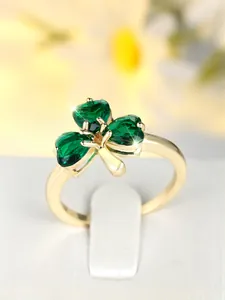 Macro detail of golden clover ring with heart-shaped emerald green zircon stones