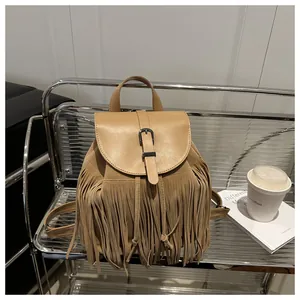 Close-up of vintage tan suede backpack with long tassels and metallic buckle detail