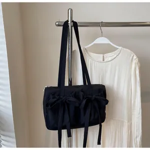 Détail d'un sac cabas noir avec deux nœuds décoratifs sur tissu en nylon lisse