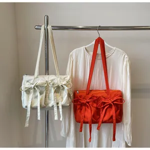 Détail des poches à nœuds sur les sacs fourre-tout en nylon crème et orange stylés
