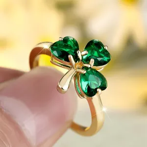 Golden clover ring with three emerald heart-shaped stones on a minimalist polished band