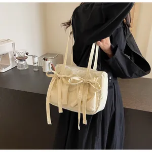Vue détaillée du sac cabas beige avec grands nœuds et finition en tissu texturé