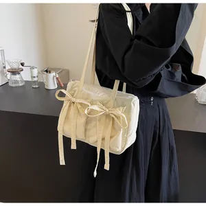 Détail du grand sac cabas crème avec des nœuds décoratifs et un tissu en nylon froissé