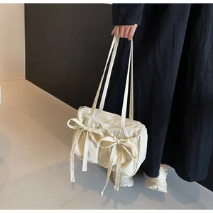 Détail du sac cabas crème à nœud montrant le tissu en nylon plissé et la fermeture