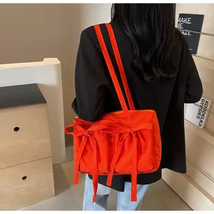 Vue détaillée du grand sac cabas orange avec rubans à nœuds et poches extérieures