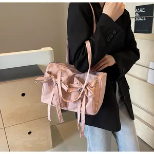 Sac fourre-tout en nylon rose avec nœuds et fermeture éclair porté à l'épaule par un mannequin