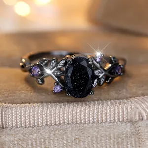 Vintage black vine ring with oval blue sandstone and purple accents in a gift box