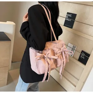 Gros plan d'un sac cabas plissé rose avec de grands nœuds porté à l'épaule sur modèle