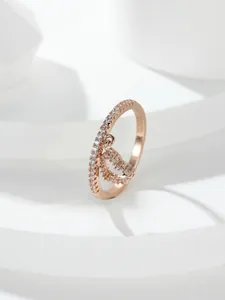 Dettaglio macro di un anello in oro rosa con ciondolo a lettera D e pavé di zirconi lucidi
