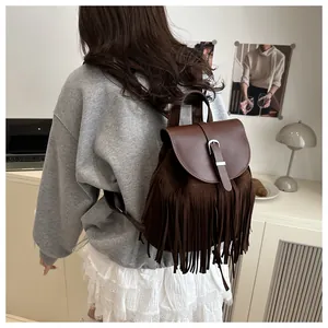 Detail of dark brown backpack featuring suede tassels and silver buckle in home office setting