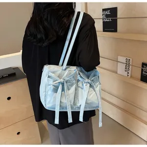 Détail d'un sac cabas bleu clair avec des nœuds et une texture plissée sur un mannequin