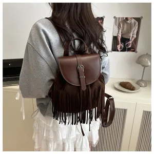 Detailed view of a vintage brown leather backpack with long tassels in a minimalist setting