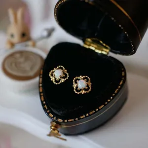 Makroansicht von Vintage-Ohrringen mit weißem Opal in einer herzförmigen Geschenkbox