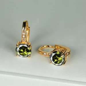 Dettaglio di orecchini placcati in oro con pietra rotonda verde e micro-diamanti scintillanti