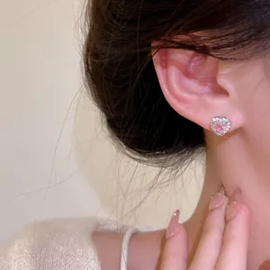 Pink heart-shaped zircon earrings with silver-toned plating worn on a model's ear
