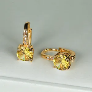 Dettaglio di orecchini a cerchio placcati in oro con grande zircone giallo e piccoli accenti