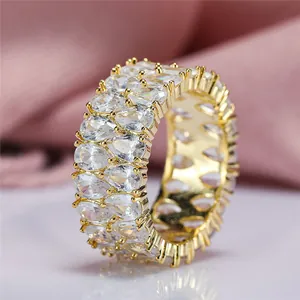 Elegant gold double-row pear-cut zircon eternity ring on soft pink silk background