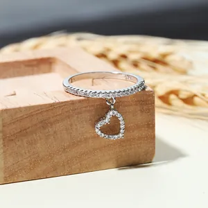 Anello in argento 925 con ciondolo a cuore e diamanti scintillanti su supporto in legno