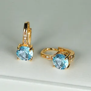Dettaglio orecchino a cerchio dorato con grande zircone blu e piccoli diamanti