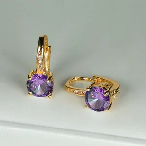 Dettaglio di orecchini a cerchio dorati con grande zircone viola rotondo e piccoli cristalli