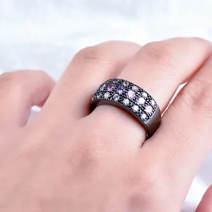 Women's black metal wide ring with pavé-set pink and purple zircon stones in macro view