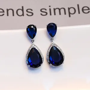 Makroaufnahme von Silberohrringen mit blauen Saphiren in Birnenform und Zirkonia-Halo