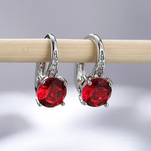 Dettaglio macro di orecchini in argento con grande zircone rosso e montatura pavé