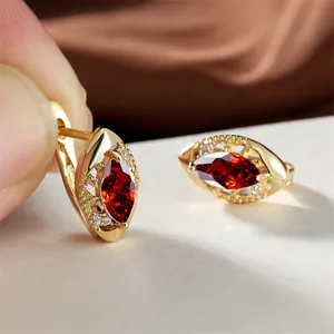 Détail de créoles dorées avec zircon rouge taille marquise et motifs évidés élégants