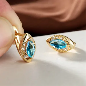 Vue macro des boucles d'oreilles en or avec pierre marquise bleue et détails ciselés