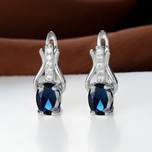 Detail von silbernen Ohrhängern mit tiefblauem ovalem Edelstein und kleinen Zirkonia