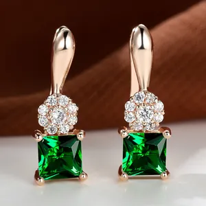 Detailed close-up of square emerald zircon earrings with champagne gold floral setting