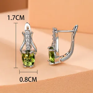 Makro-Detail von goldfarbenen Ohrringen mit grünem ovalem Edelstein und Zirkon-Inlay