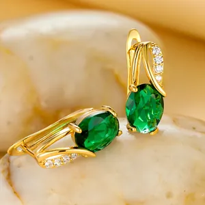 Macro detail of oval green zircon earrings with champagne gold finish and stones
