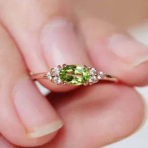 Dettaglio dell'anello in oro rosa con peridoto ovale e piccoli diamanti laterali