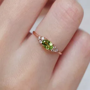 Anello in oro rosa con peridoto ovale e zirconi micro-pavé indossato sulle dita