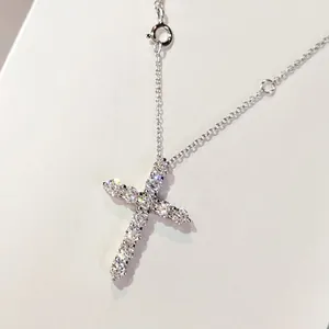 Dettaglio del ciondolo a croce in argento con zirconi blu su una sottile catena a maglia
