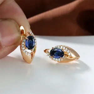 Dettaglio macro di orecchini in oro champagne con pietra blu ovale e cristalli incastonati