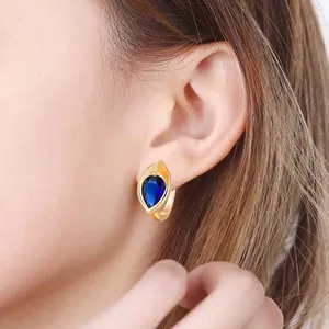 Élégantes boucles d'oreilles créoles dorées avec zircon bleu portées par un mannequin