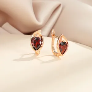 Gros plan de boucles d'oreilles goutte or champagne avec zircon rouge sur soie