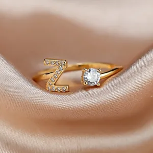 Detail view of gold open ring featuring letter Z design with zircon and round stone