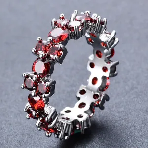 Macro-opname van een zilveren ring bezet met rode ronde zirkoniasteentjes rondom de hele band