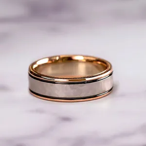 Gros plan macro d'une bague bicolore en or rose et argent brossé sur du marbre
