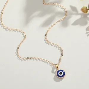 Turkish Evil Eye pendant necklace with a golden chain on a minimal textured background
