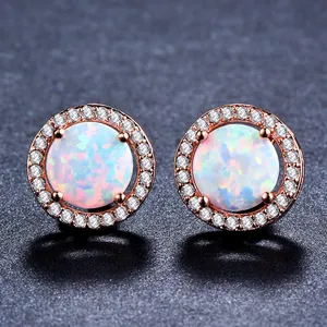 Détail macro de boucles d'oreilles rondes en or rose avec opales et petits diamants blancs